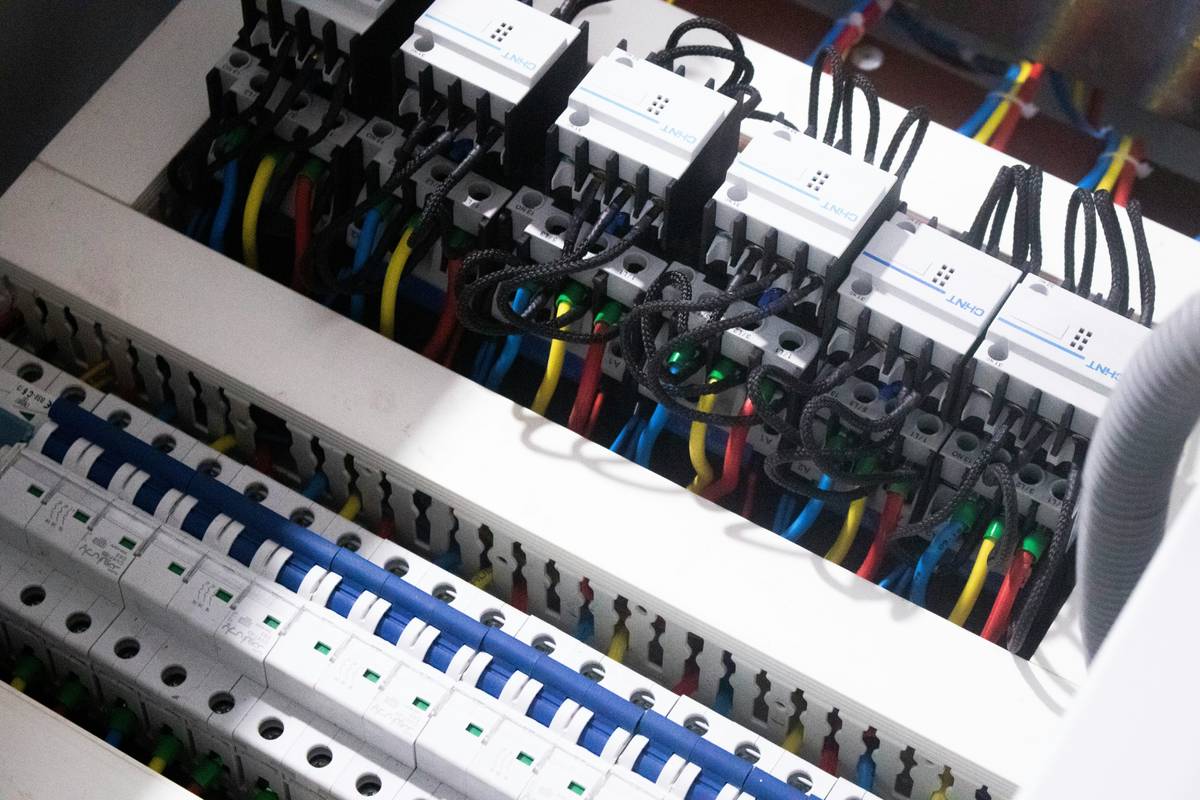 Close-up of hands wiring a solar combiner box with electrical wiring panel how to wire labels visible